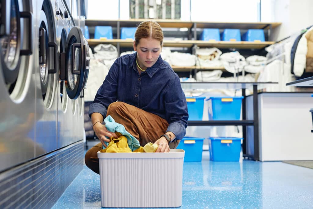 woman loading clothes into washing machine self service laundry