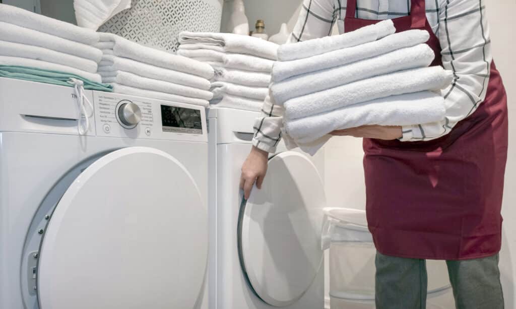 worker hotel holds lot towels hands near dry machine laundry